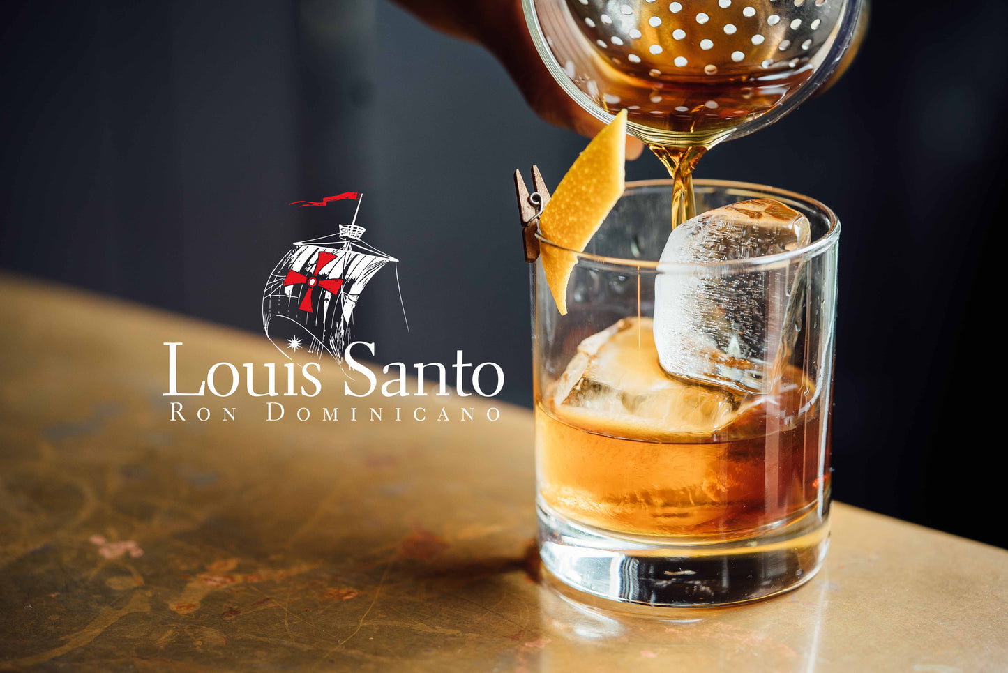 Werbung Louis Santo Ron Dominicano mit einem Tumbler Glas, einer Orangenhaut Spitze, in den ein Rum eingegossen wird