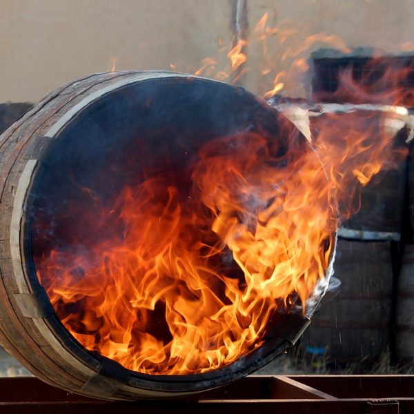 Ein Eichenfass wird mit Feuer ausgebrannt um den excellenten rauchigen Geschmack während der Fassreifung zu erzeugen